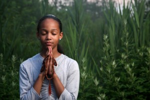 Teenage girl praying outdoors at twilight. Shallow DOF.